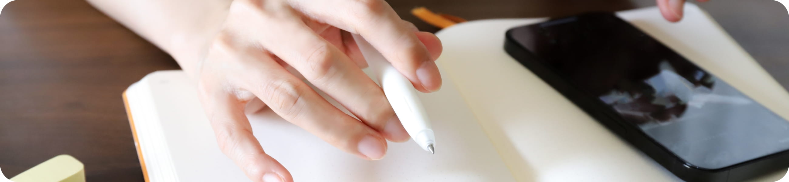 ペンを持ってメモを取る手元